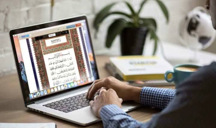 Adult studying the Quran on a laptop at home