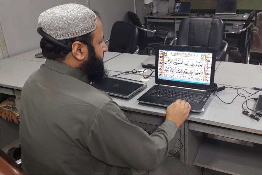 Male Quran tutor delivering an online lesson from a classroom